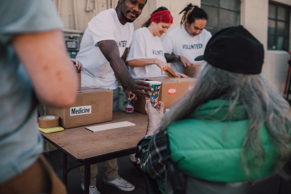 Volunteer handing a drink to a visitor at a donation table